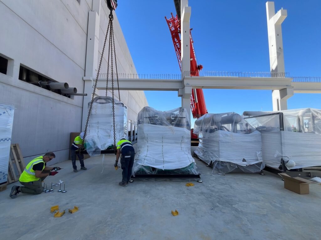 Descarga con grúa de los equipos de refrigeración en la obra de la plataforma logística