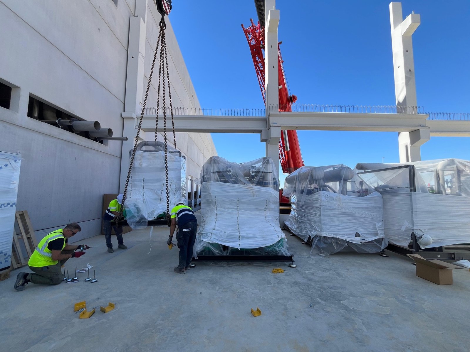 Descarga con grúa de los equipos de refrigeración en la obra de la plataforma logística